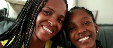 Two women sitting together, smiling on a couch.